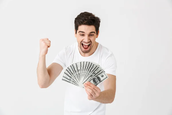 Schockiert aufgeregt glücklich junger Mann posiert isoliert über weiße Wand Hintergrund hält Geld. — Stockfoto