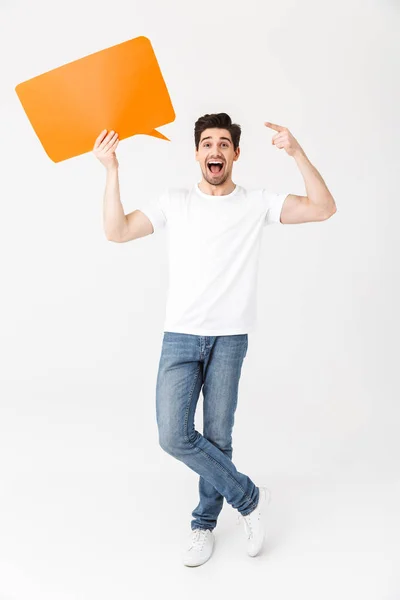 Emotional excited young man posing isolated over white wall background holding speech bubble. — Stock Photo, Image