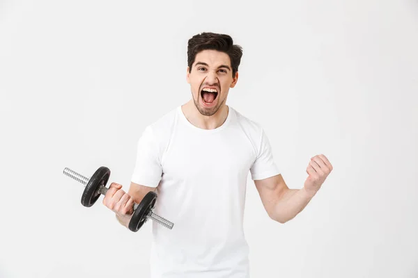 Cris excités jeune homme posant isolé sur mur blanc tenant haltère faire de l'exercice . — Photo