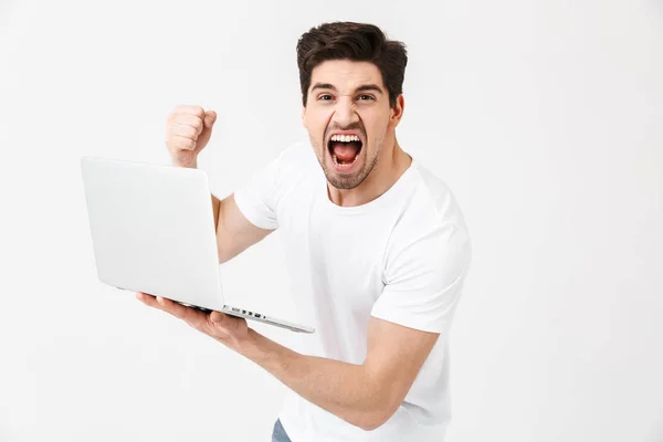 Cris jeune homme posant isolé sur un mur blanc à l'aide d'un ordinateur portable . — Photo