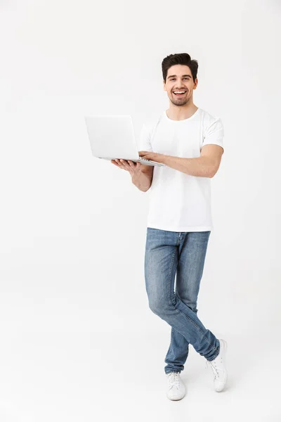 Aufgeregter junger Mann posiert isoliert mit Laptop über weißer Wand. — Stockfoto