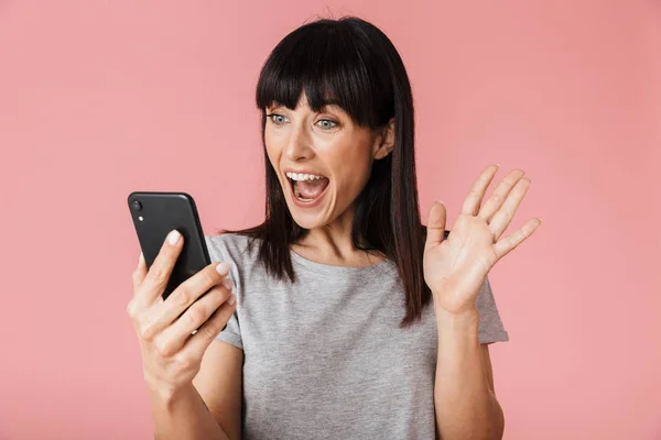 Increíble mujer feliz emocionada posando aislada sobre la pared de fondo rosa claro usando el teléfono móvil — Foto de Stock