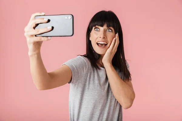 Increíble mujer feliz emocionada posando aislada sobre la pared de fondo rosa claro usando el teléfono móvil —  Fotos de Stock