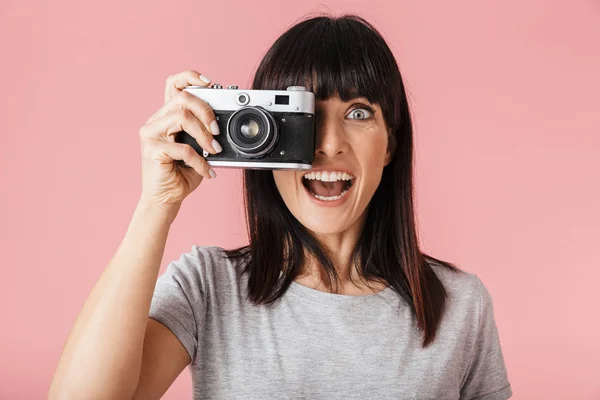 Eccitato felice donna fotografo posa isolato su luce rosa sfondo parete con fotocamera . — Foto Stock