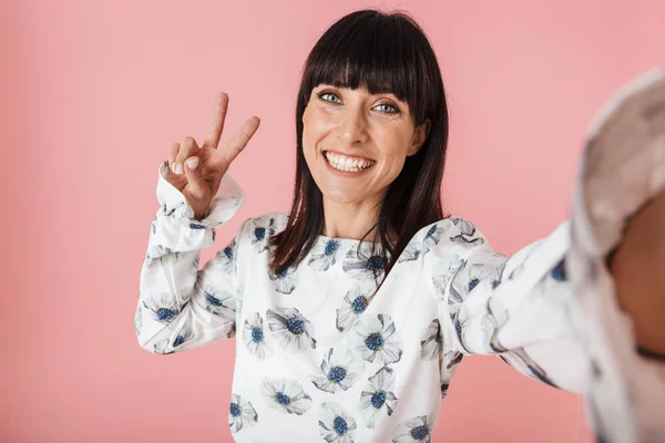 Mooie gelukkige jonge vrouw poseren geïsoleerd over roze muur achtergrond Neem selfie door camera. — Stockfoto