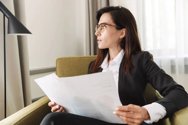 Junge Geschäftsfrau in formeller Kleidung zu Hause bei der Arbeit mit Dokumenten und Grafiken. — Stockfoto