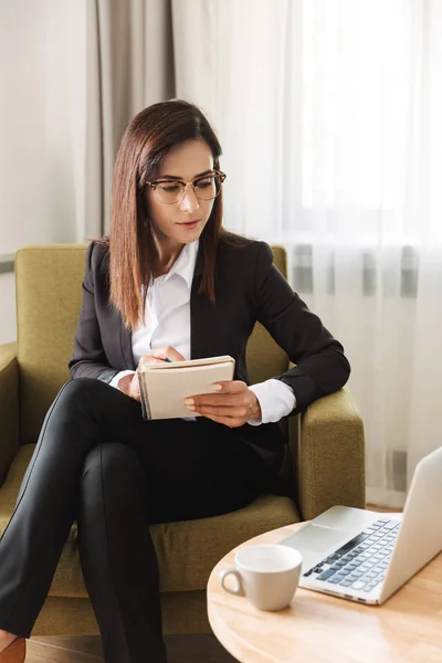 Young business woman in formal wear clothes indoors at home work with laptop computer writing notes. — Stock Photo, Image