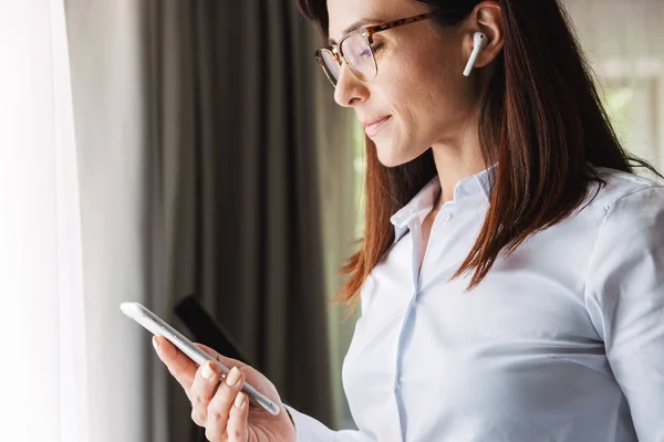 Amazing Happy vackra unga affärskvinna i formella kläder inomhus hemma pratar med mobiltelefon lyssnar musik med hörlurar med telefon. — Stockfoto