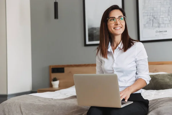 Retrato de alegre mujer de negocios adulta escribiendo en el ordenador portátil, mientras que si —  Fotos de Stock