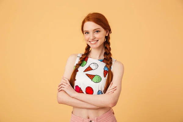 Sorridente bella rossa donna vestita di gelato stampato t-shirt posa isolato su sfondo giallo . — Foto Stock