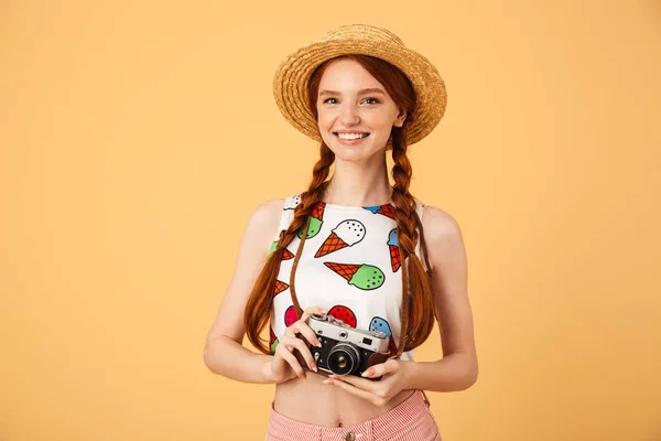 행복 한 젊은 아름 다운 빨간 머리 여자 사진 작가 관광객 옷을 입고 아이스크림 인쇄 티셔츠 포즈 위에 고립 된 노란색 배경 들고 카메라. — 스톡 사진