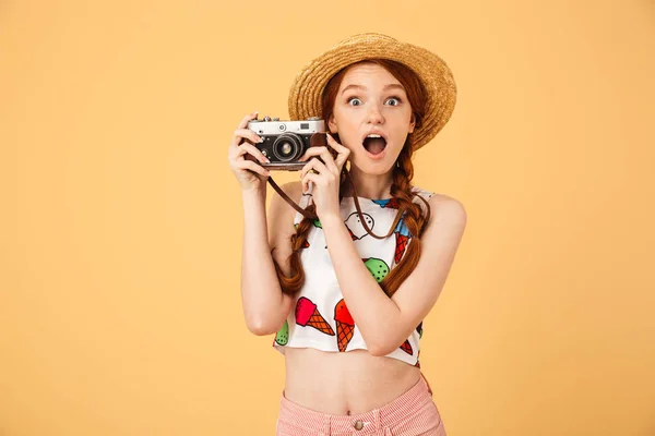 पिवळा पार्श्वभूमी धारणा कॅमेरा प्रती वेगळे पोझिंग आयस्क्रीम मुद्रित टी-शर्ट मध्ये परिधान तरुण सुंदर रेडहेड महिला छायाचित्रकार पर्यटक धक्का बसला . — स्टॉक फोटो, इमेज