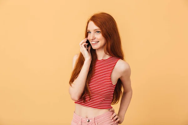 행복 한 젊은 아름 다운 빨간 머리 여자 포즈 고립 된 위에 노란색 배경 이야기 로 휴대 전화. — 스톡 사진
