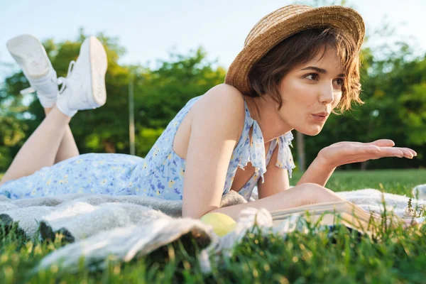 Mooie jonge mooie vrouw ligt op gras in Park buitenshuis lezen boek. — Stockfoto