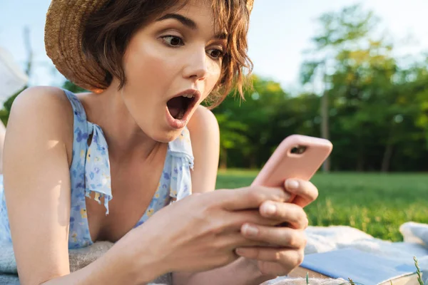 Bella scioccato giovane bella donna nel parco verde all'aperto utilizzando il telefono cellulare . — Foto Stock