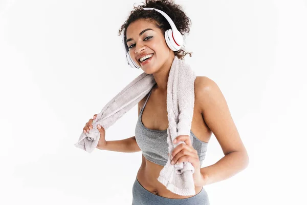 Beautful fiatal csodálatos boldog sport fitness afrikai nő hallgat zenét fejhallgató gazdaság törülköző. — Stock Fotó