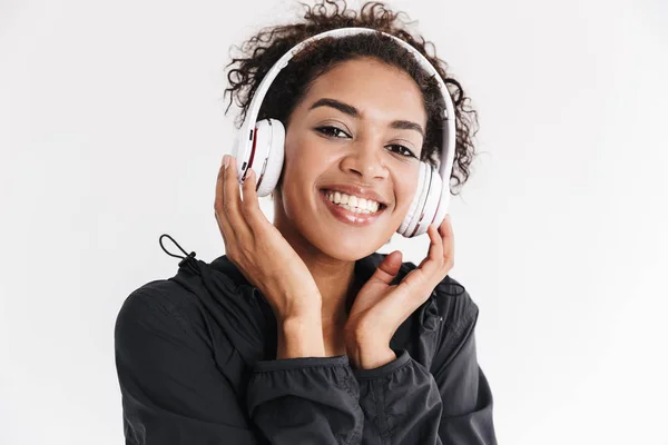 Bonito jovem incrível esportes aptidão mulher africana ouvir música em fones de ouvido isolados sobre fundo branco . — Fotografia de Stock