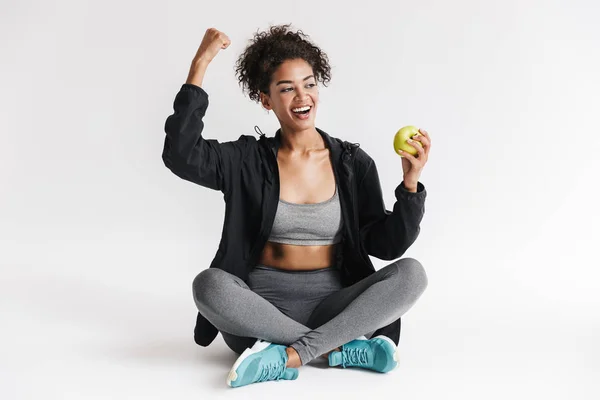 Beautful młody niesamowite sportowe fitness African kobieta jeść jabłko na białym tle. — Zdjęcie stockowe