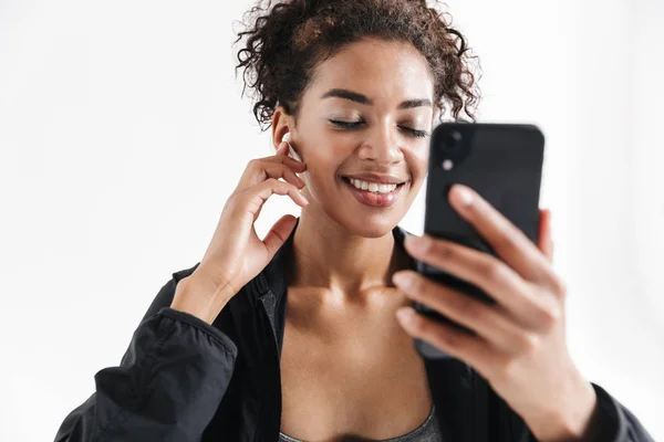 Nuori hämmästyttävä urheilu kunto afrikkalainen nainen käyttää matkapuhelin kuuntelee musiikkia . — kuvapankkivalokuva