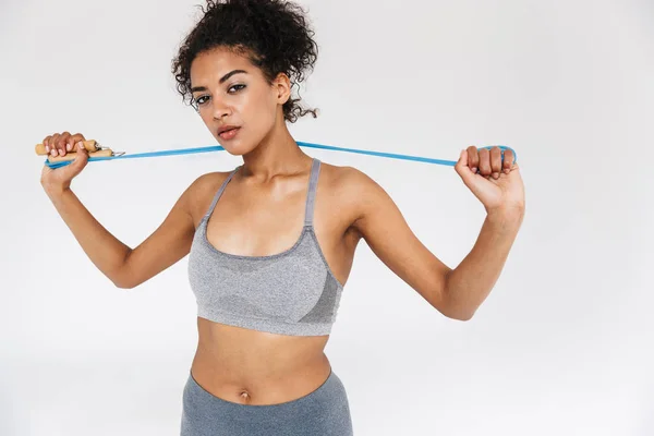 Young amazing sports fitness african woman posing isolated over white background holding skipping rope. — Stock Photo, Image