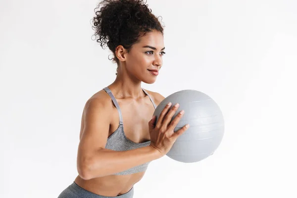 Joven increíble deporte fitness mujer africana posando aislado sobre fondo blanco hacer ejercicios con pelota . —  Fotos de Stock
