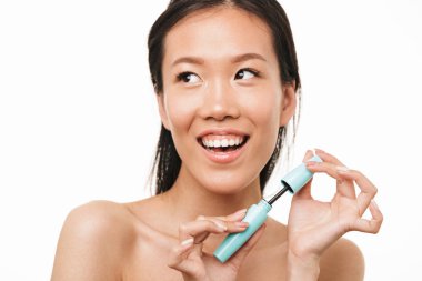 Güzel asyalı kadın makyaj maskara tutarak beyaz duvar arka plan üzerinde izole poz.