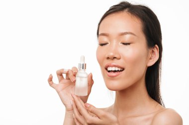 Serum yağı tutan beyaz duvar arka plan üzerinde izole poz sağlıklı bir cilt ile genç güzel kadın.