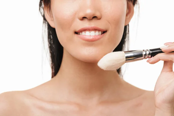 Feliz jovem bela asiática mulher posando isolado sobre branco parede fundo segurando maquiagem escova . — Fotografia de Stock
