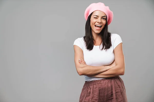 Linda joven optimista complacida francesa en boina posando aislada sobre fondo de pared gris guiñando con los brazos cruzados . —  Fotos de Stock