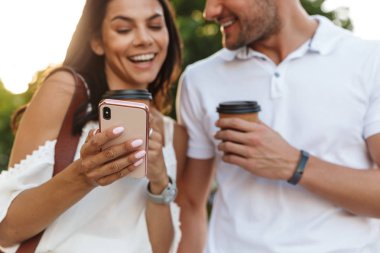 Yürürken akıllı telefon kullanan mutlu genç çiftin portresi