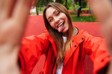 Yağmurluk giyen chherful çekici genç kız