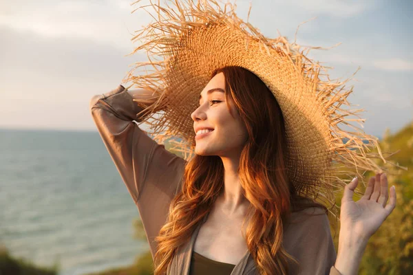 Szép fiatal csinos nő kalapot jelentő kültéri tenger közelében a tengerparton. — Stock Fotó