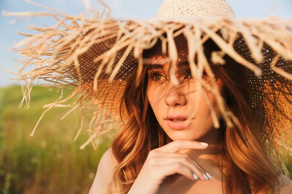 Hermosa joven bonita mujer en sombrero posando al aire libre en la naturaleza hierba verde cerca de la playa . — Foto de Stock
