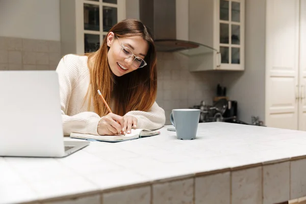 Atraktivní mladá dívka, která sedí doma v kuchyni — Stock fotografie