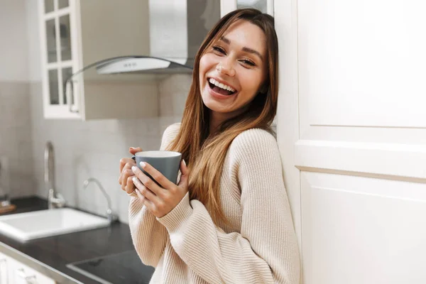 Hermosa chica joven bebiendo té en una cocina — Foto de Stock