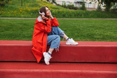 Yağmurluk giyen chherful çekici genç kız