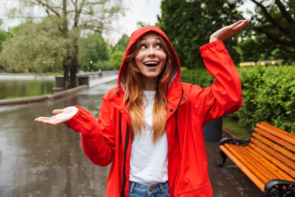 Imagen de mujer joven europea de 20 años en impermeable colorido caminando t —  Fotos de Stock