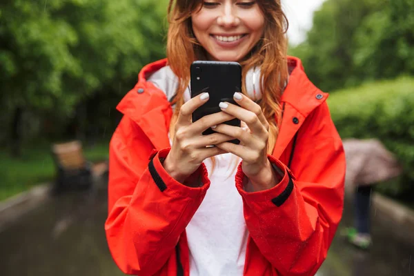 Bild av lycklig ung kvinna som innehar mobiltelefon medan du går — Stockfoto