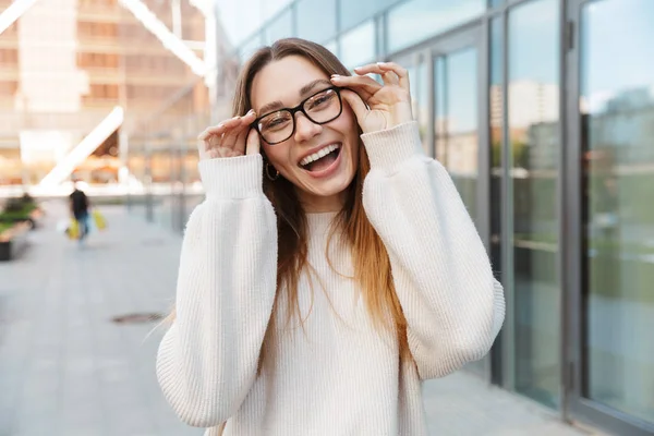 Gyönyörű, fiatal, boldog, izgalmas üzleti nő, pózol a szabadban, közel üzleti központ viselése szemüvegek. — Stock Fotó