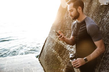 Yakışıklı genç sporcu cep telefonu kullanarak