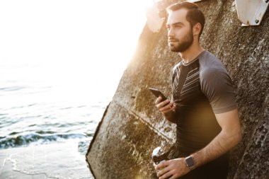 Yakışıklı genç sporcu cep telefonu kullanarak