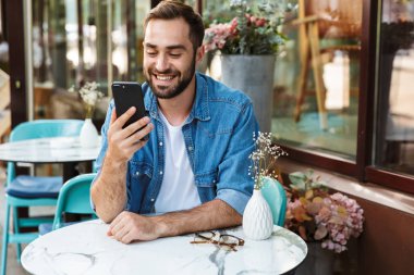 Kafe masasında oturan yakışıklı gülümseyen adam