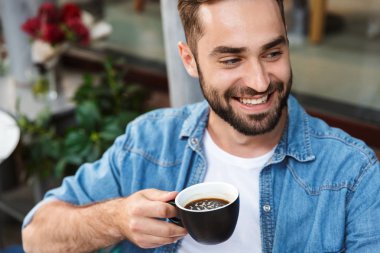 Kafe masasında oturan yakışıklı gülümseyen adam