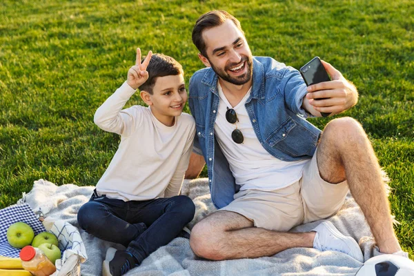 Feliz joven padre haciendo un picnic con su pequeño hijo — Foto de Stock