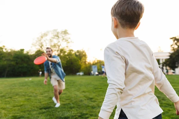 Giovane uomo divertirsi con il suo fratellino o figlio outoors nel parco bella erba verde gioco . — Foto Stock