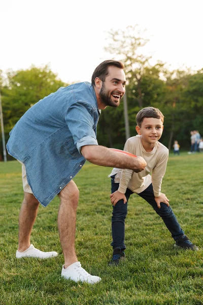 Juegos Joven divirtiéndose con su hermano pequeño o hijo en el parque hermoso juego de hierba verde juego . — Foto de Stock