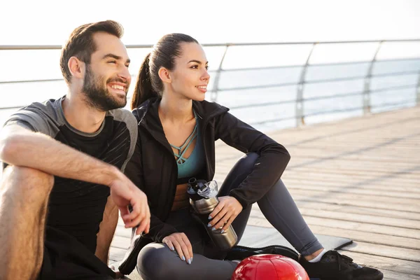 Alegre jovem casal desportivo sentado em um tapete de fitness — Fotografia de Stock