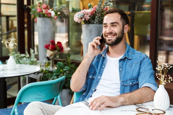 Schöner lächelnder Mann sitzt am Cafétisch — Stockfoto