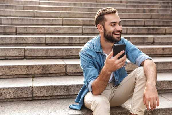 Sonriente joven sentado en las escaleras al aire libre — Foto de Stock