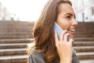 Açık havada merdivenlerde oturan neşeli genç kız